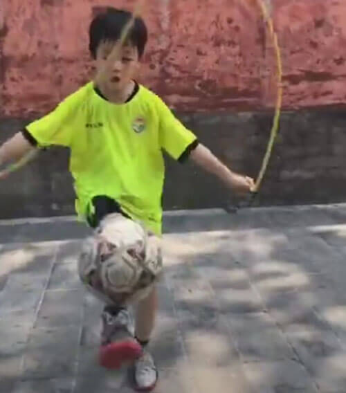 Ловкий мальчик справляется одновременно и с мячом, и со скакалкой