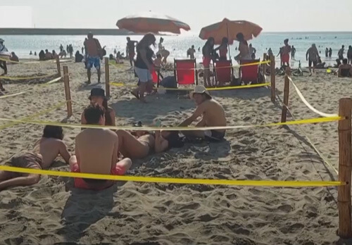 Придя на пляж, отдыхающие сидят в огороженных квадратах ради соблюдения дистанции