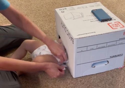 Чтобы поменять сыну подгузник, мама накрывает ребёнка коробкой